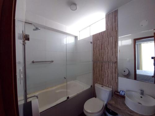 y baño con aseo, bañera y lavamanos. en Hotel Golf Paracas en Paracas