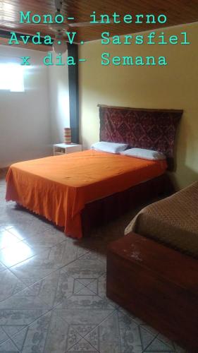 een slaapkamer met een bed met een oranje sprei bij Edificio Salguero in Leandro N. Alem