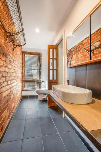 a bathroom with a large tub and a brick wall at The Panoramic Tree View Home in Melbourne City in Melbourne