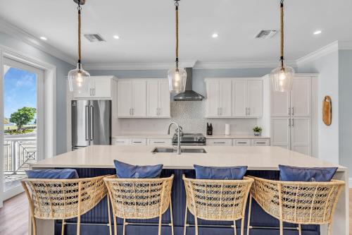 a kitchen with white cabinets and a island with chairs at Brand New Luxury Oceanfront Home w Pool, 38' Slip in Marathon