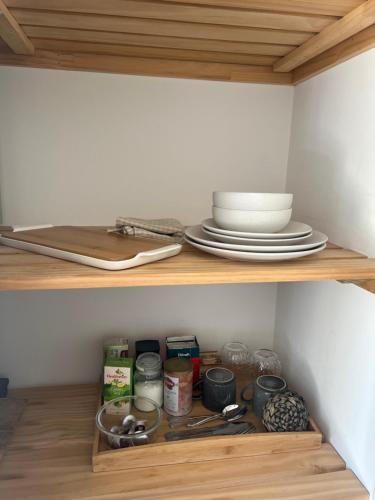 a shelf with plates and dishes on top of it at Private by the beach in Whitianga