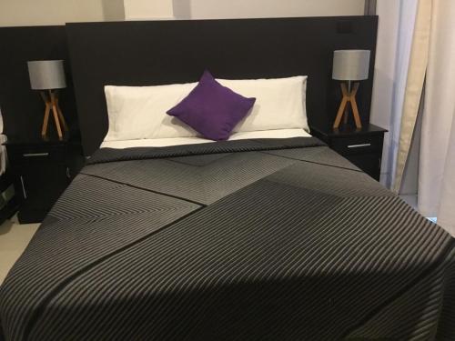 a black and white bed with a purple pillow at Hotel Tao in Atlixco