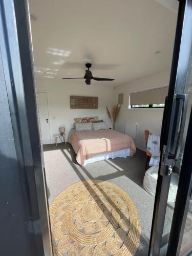 une chambre avec un lit et un ventilateur de plafond dans l'établissement Paradise by Simpsons beach, à Whitianga