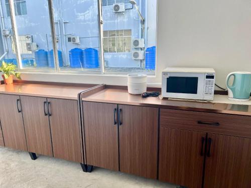 a desk with a microwave and a window in an office at Theresa's Homestay in Tawau