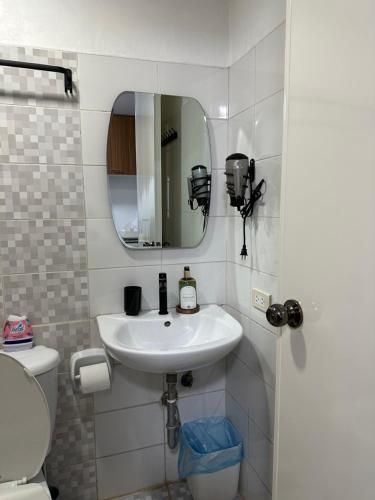 a bathroom with a sink and a toilet and a mirror at Condo in Ortigas in Manila