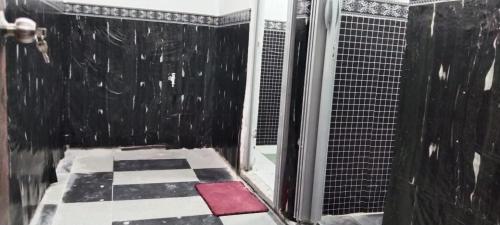 ein Bad mit einer Dusche und einem schwarz-weißen Boden in der Unterkunft D'Bukit Homestay in Pengerang