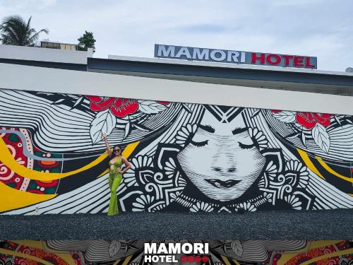 a woman standing in front of a mural on a building at MAMORI HOTEL in Allen