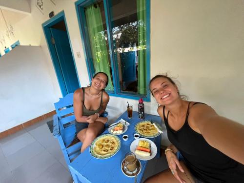 two women sitting at a table with food on it at Melbao Homestay in Gili Air