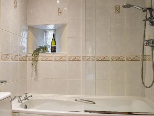 Waltham on the Wolds的住宿－The Stables，带浴缸和一瓶葡萄酒的浴室。