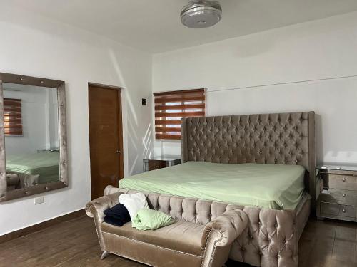 a bedroom with a bed and a couch with a mirror at Villas regazó de paz, ven a buscar tu paz en la naturaleza in Concepción de La Vega