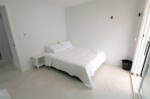 Dormitorio blanco con cama blanca con sábanas y almohadas blancas en WoW WoW Pool Villa en Gyeongju
