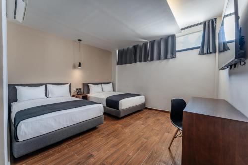 a hotel room with two beds and a desk at Hotel Mexico, Merida in Mérida