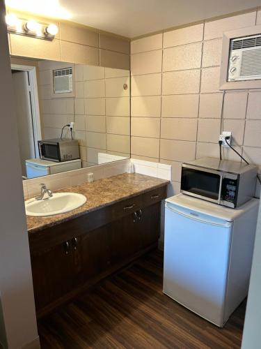 a bathroom with a sink and a microwave at Goodknight Inn in Lloydminster