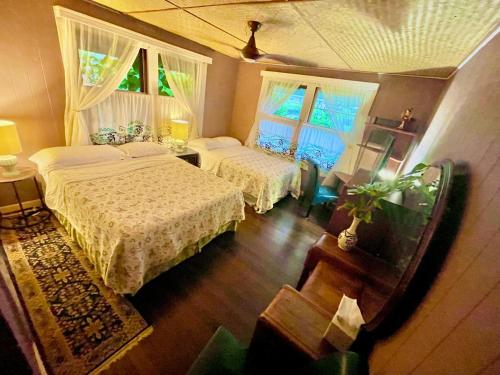 1 dormitorio con 2 camas y 2 ventanas en Shaka Shak Guest House, en Hilo
