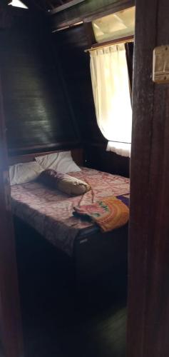 ein kleines Bett in einem kleinen Zimmer mit Fenster in der Unterkunft villa kayu argapuri resort ciwidey in Pengalongan