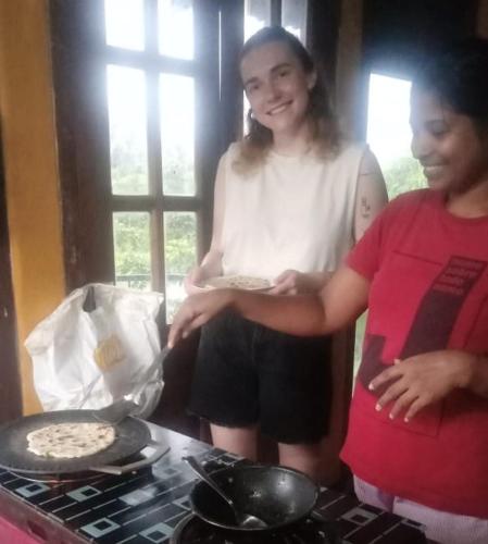 two women standing next to a stove with a pizza at Coca Cola Hostel Malabe in Malabe