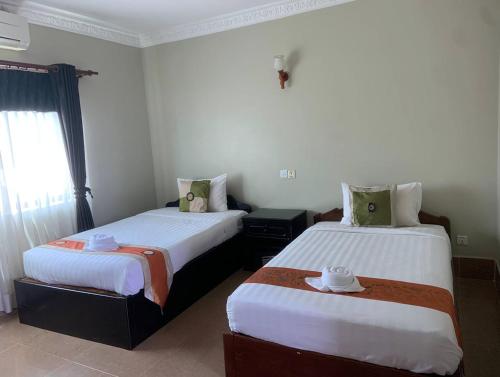 a bedroom with two beds and a window at Central Night Hotel in Siem Reap