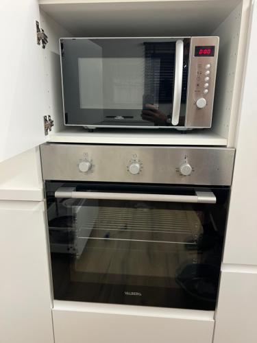 un forno a microonde posto sopra un forno da cucina di Charmant appartement au look design a Mons
