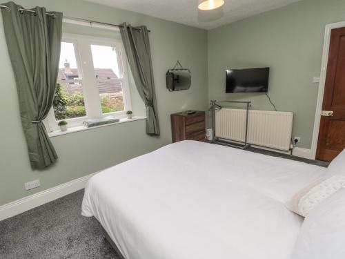 a bedroom with a white bed and a television at Prudhoe Cottage in Prudhoe