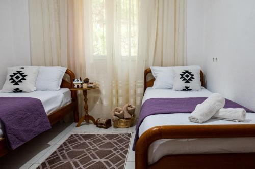 a bedroom with two beds and a window with curtains at Panoramic View House in Tepelenë