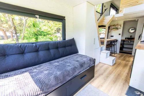 - un salon avec un canapé bleu dans une petite maison dans l'établissement Mini maison Tiny house 6 per 3800m2 jardin Jacuzzi, à Pontault-Combault