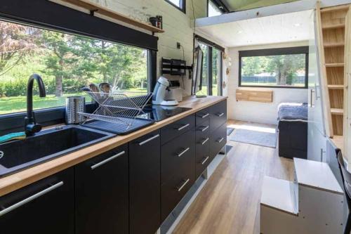 une cuisine avec un évier et une grande fenêtre dans l'établissement Mini maison Tiny house 6 per 3800m2 jardin Jacuzzi, à Pontault-Combault