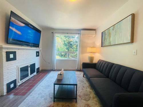 a living room with a couch and a flat screen tv at Super Privacy Lakeshore Forest Home with Air Conditioners at Haller Lake in Seattle