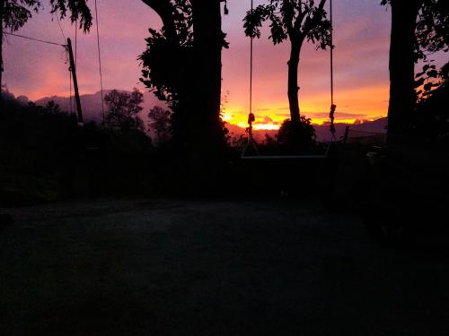 a sunset with trees in the foreground at HOME HOSTEL ELLA private rooms only in Ella