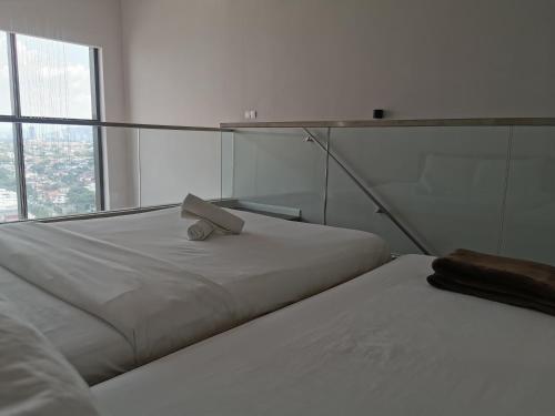 two beds in a white room with a laptop on top at Icon Residenz Icon City, Petaling Jaya by De Harlequins Guesthouse in Petaling Jaya