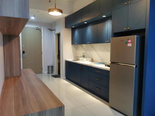 a kitchen with blue cabinets and a refrigerator at Icon Residenz Icon City, Petaling Jaya by De Harlequins Guesthouse in Petaling Jaya