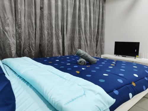 a bed with a blue comforter and a television at Icon Residenz Icon City, Petaling Jaya by De Harlequins Guesthouse in Petaling Jaya