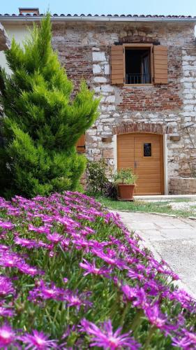 a garden with purple flowers in front of a building at Holiday Home Old Barn in Umag