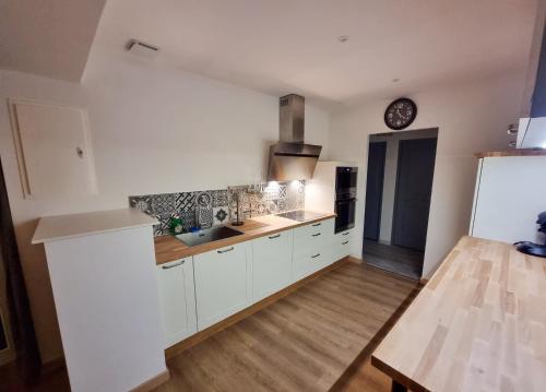 une cuisine avec des placards blancs et une horloge murale dans l'établissement Maison 700m du centre-ville, à Auxerre