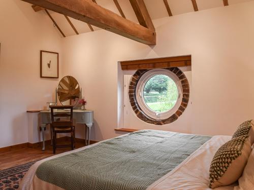 a bedroom with a bed and a round window at The Barn in Nantwich