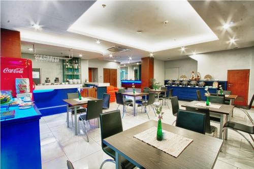 um restaurante com mesas e cadeiras e um balcão em Javein Griyadi Hotel em Jakarta