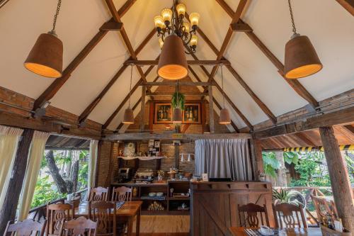 a dining room with wooden tables and chairs and large windows at Le Charcoa Hotel in Chiang Mai