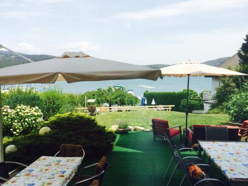 a patio with tables and chairs and umbrellas at Wörthersee Appartements Lex in Maria Wörth