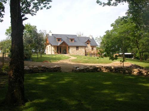 une grande maison en pierre avec un arbre en face de celle-ci dans l'établissement Gîte Marzan, à Marzan