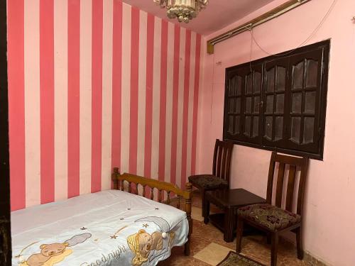 a small bedroom with a bed and two chairs at شقه ثلاثه غرف وريسبشن ثلاثه قطع لك بالكامل بها تكييف ف الصاله in Mansoura