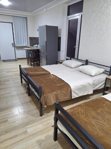 a bedroom with two beds and a kitchen with a refrigerator at GUEST HOUSE 15A in Kutaisi