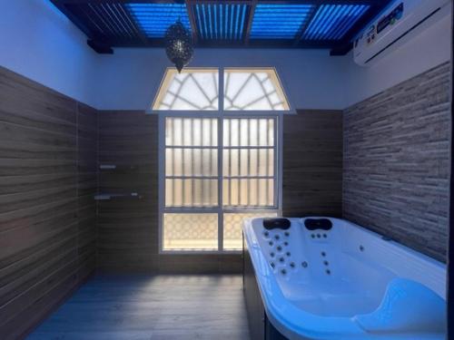 a large bathroom with a tub and a window at A'Sinamar Hotel Apartment in Muscat