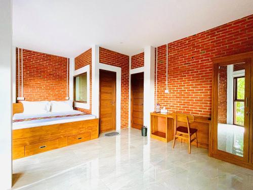 een slaapkamer met een bed, een bureau en een bakstenen muur bij Puu Pau Hotel & Coffee Shop in Labuan Bajo
