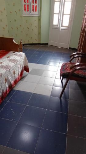 a bedroom with a blue tiled floor with a bed and a chair at غرفه واحده فقط داخل شقه بها سرير ١٢٠ سم ومروحه ودولاب وكراسي in Mansoura