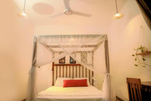a bedroom with a canopy bed with a red pillow at The villaRo in Hikkaduwa