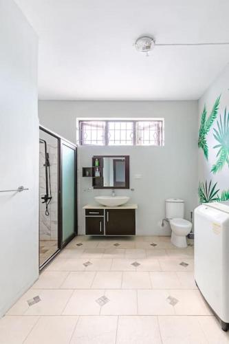 a white bathroom with a sink and a toilet at Spacious and Cosy Coastal Retreat in Albion