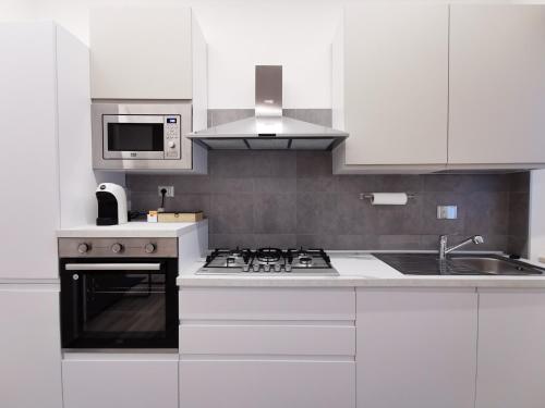 a white kitchen with a stove and a microwave at Casa Crisale in Alba