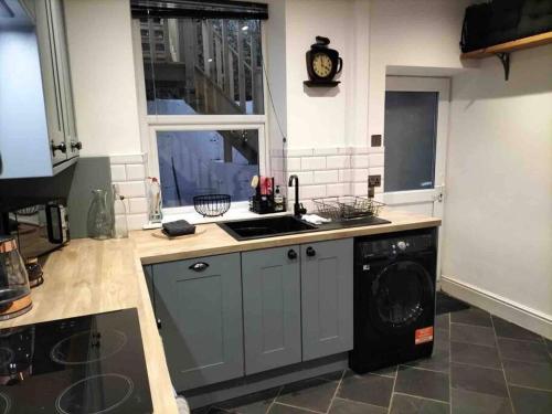 een keuken met een wastafel en een wasmachine bij Quarryman’s Holiday Let in Llysfaen