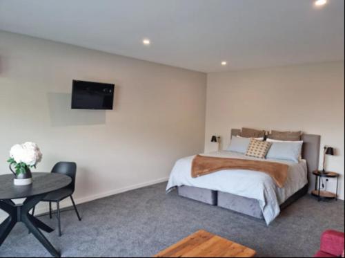 um quarto com uma cama e uma televisão na parede em Guest House on Sapphire em Wanaka