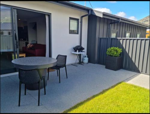 a patio with a table and chairs and a house at Guest House on Sapphire in Wanaka