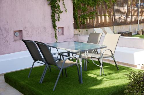 une table et des chaises en verre assises sur l'herbe dans l'établissement Nur Villa, à Karfas